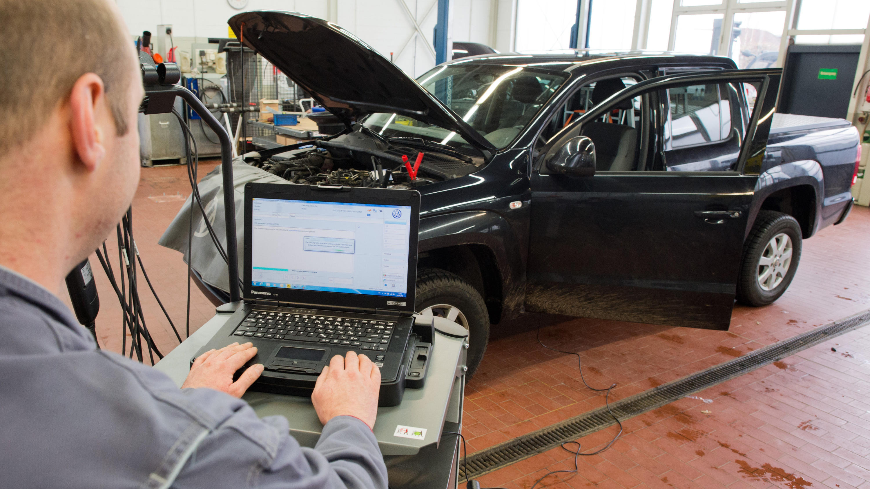 VW muss in der Dieselaffäre eine Milliarde Bußgeld zahlen ARCHIV - 27.01.2016, Niedersachsen, Hannover: Ein Kfz-Meister lädt in einer Volkswagen-Werkstatt im Rahmen der Rückrufaktion zum Abgasskandal ein Software-Update für das Steuergerät der Motorelektronik auf einen Volkswagen Amarok mit einem 2,0-Liter-