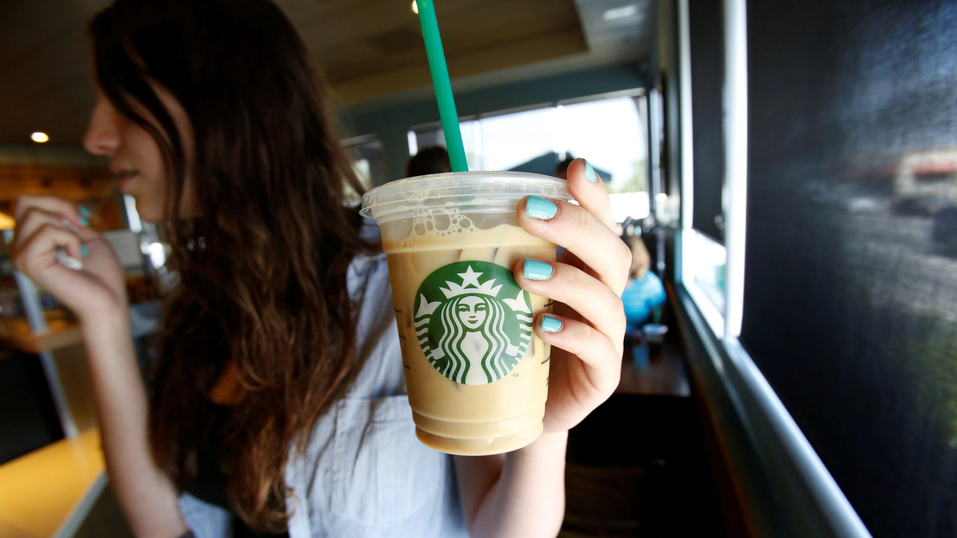 Starbucks schafft Plastik-Trinkhalme ab FILE PHOTO: A patron holds an iced beverage with a straw, at a Starbucks coffee store in Pasadena, California, U.S., July 25, 2013. REUTERS/Mario Anzuoni/File Photo
