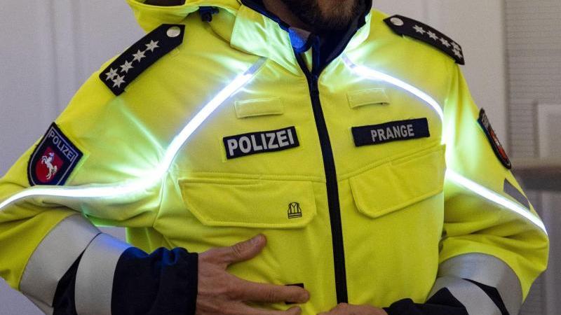 Niedersachsens Polizei erhält Blaulichtjacken und Basecaps Ein Polizeibeamter zeigt eine Blaulichtjacke