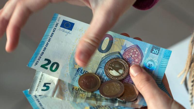 Beschäftigte belegen Platz drei beim Monatsverdienst Eine Frau hält Euro-Banknoten in den Händen