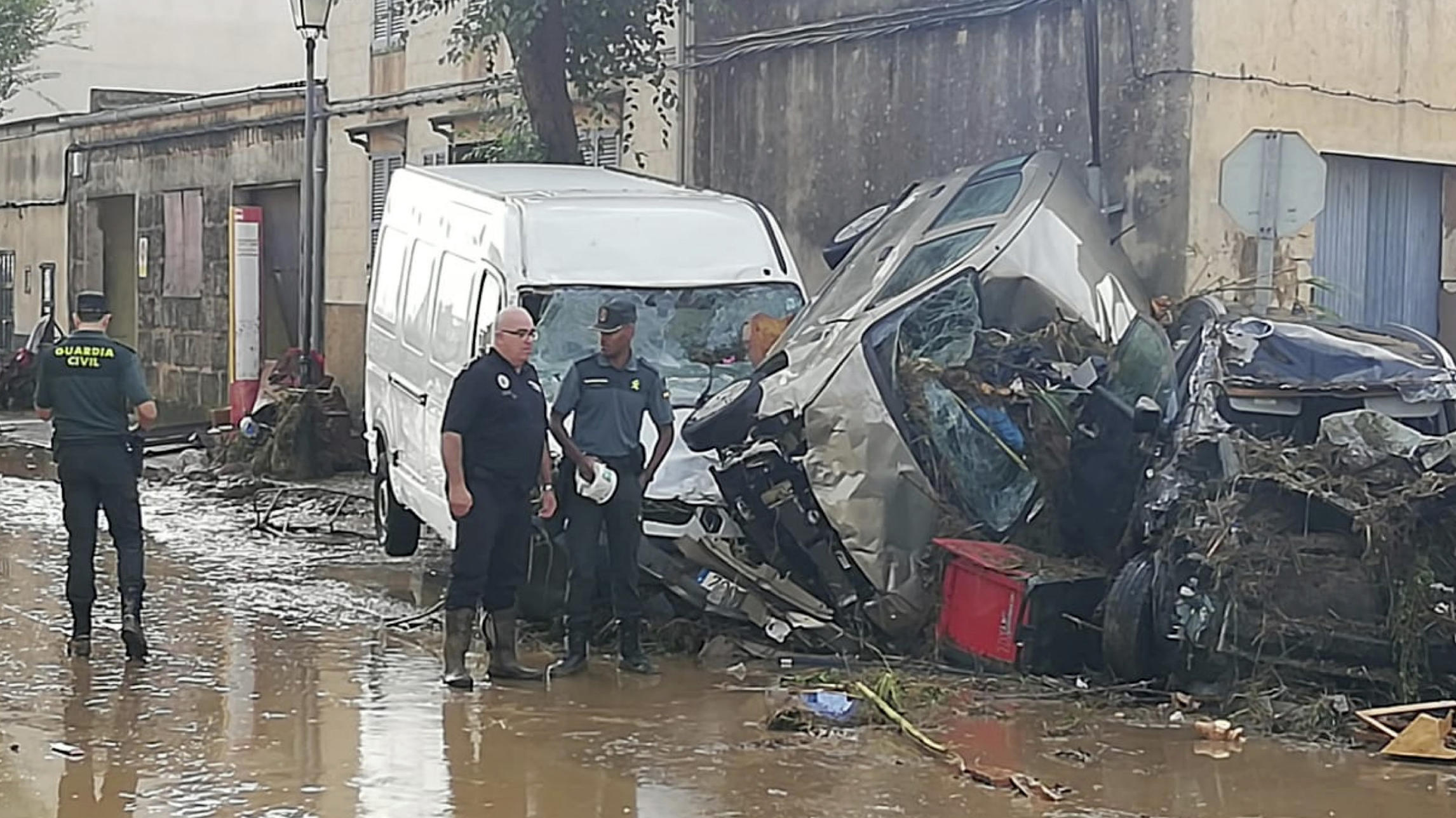 Unwetter auf Mallorca: Polizei findet zwei Leichen - in der Nähe vom Auto der deutschen Urlauber 10.10.2018, Spanien, Sant Llorenç des Cardassar: Polizeibeamte stehen auf einer Kreuzung vor zerstörten Autos, die von Starkregen und Fluten ineinander geschoben wurden. Heftige Unwetter haben auf Mallorca mindestens fünf Menschen getötet und schwere