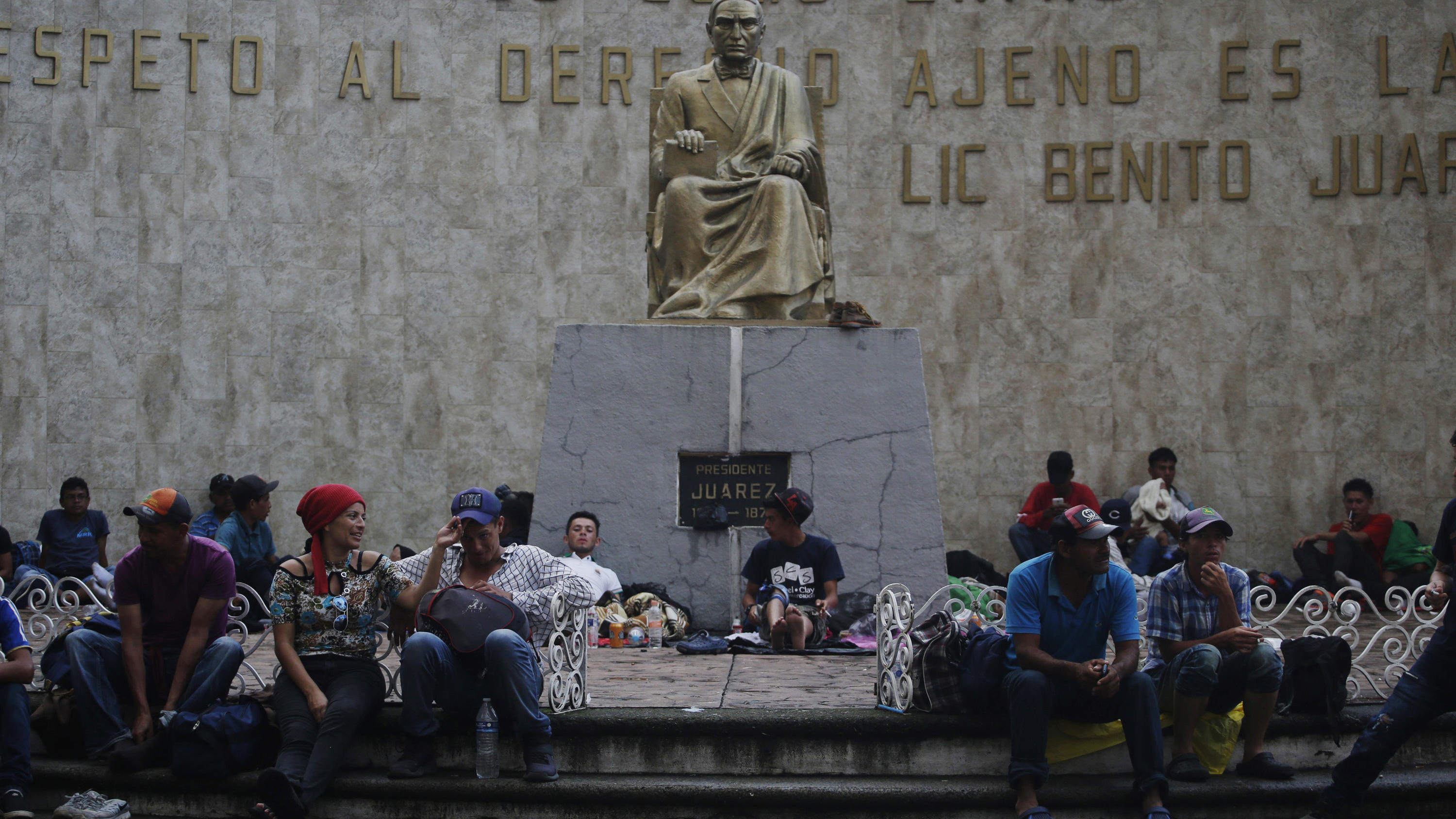 Gigantischer Exodus: Migranten strömen in Richtung USA 21.10.2018, Mexiko, Tapachula: Migranten aus Mittelamerika sitzen um eine Statue des ehemaligen mexikanischen Präsidenten Benito Juarez. Migranten aus Honduras, El Salvador und Guatemala haben den Grenzzaun zwischen Guatemala und Mexiko überwunden, u