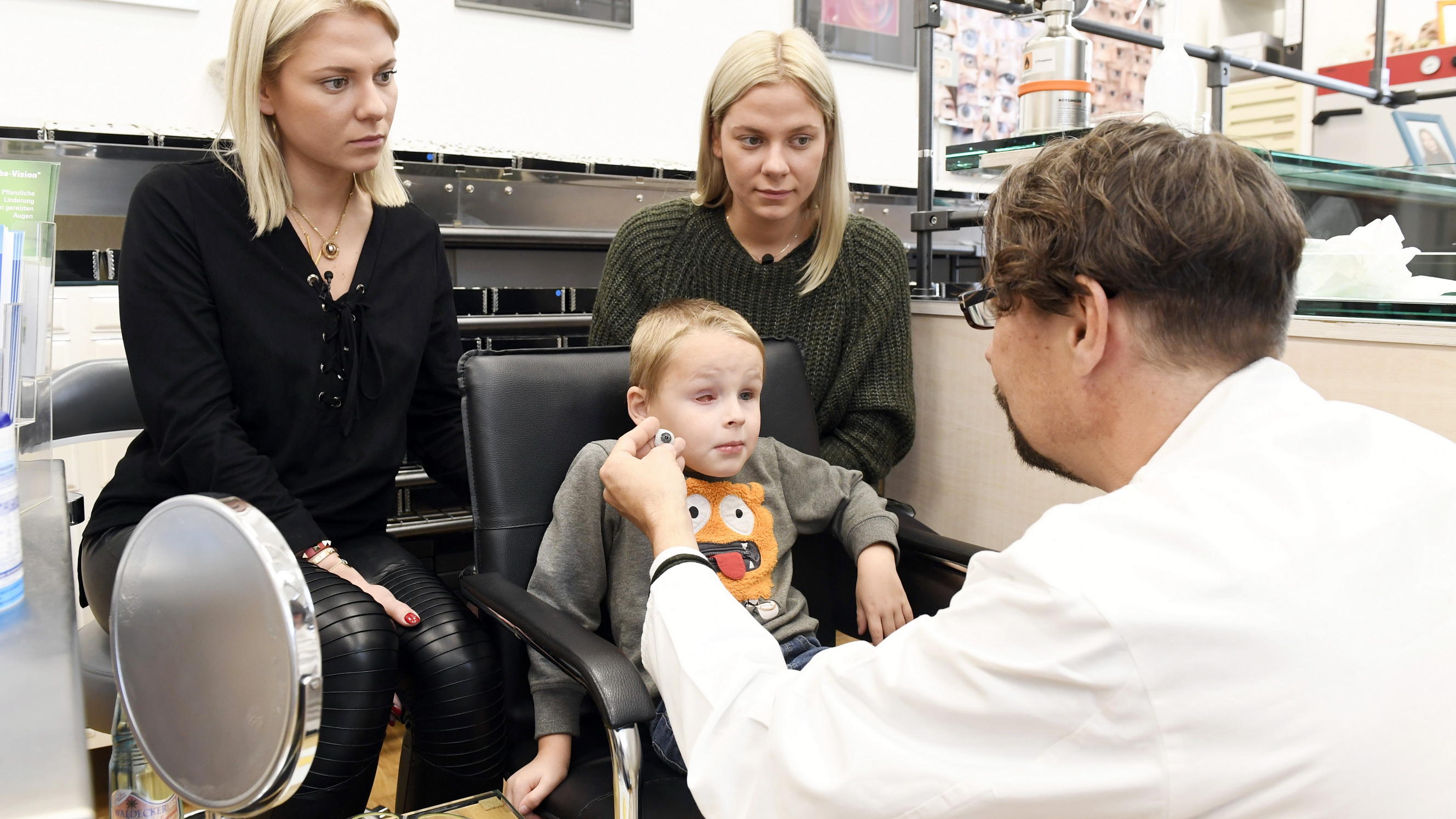"RTL – Wir helfen Kindern"-Patinnen Valentina und Cheyenne Pahde sagen dem Augenkrebs bei Kindern den Kampf an RTL- Wir helfen Kindern-Patinnen Valentina (l.) und Cheyenne Pahde (r.) mit Augenkrebspatient Till zu Besuch bei Ocularist Nicolai Weiß (r.).