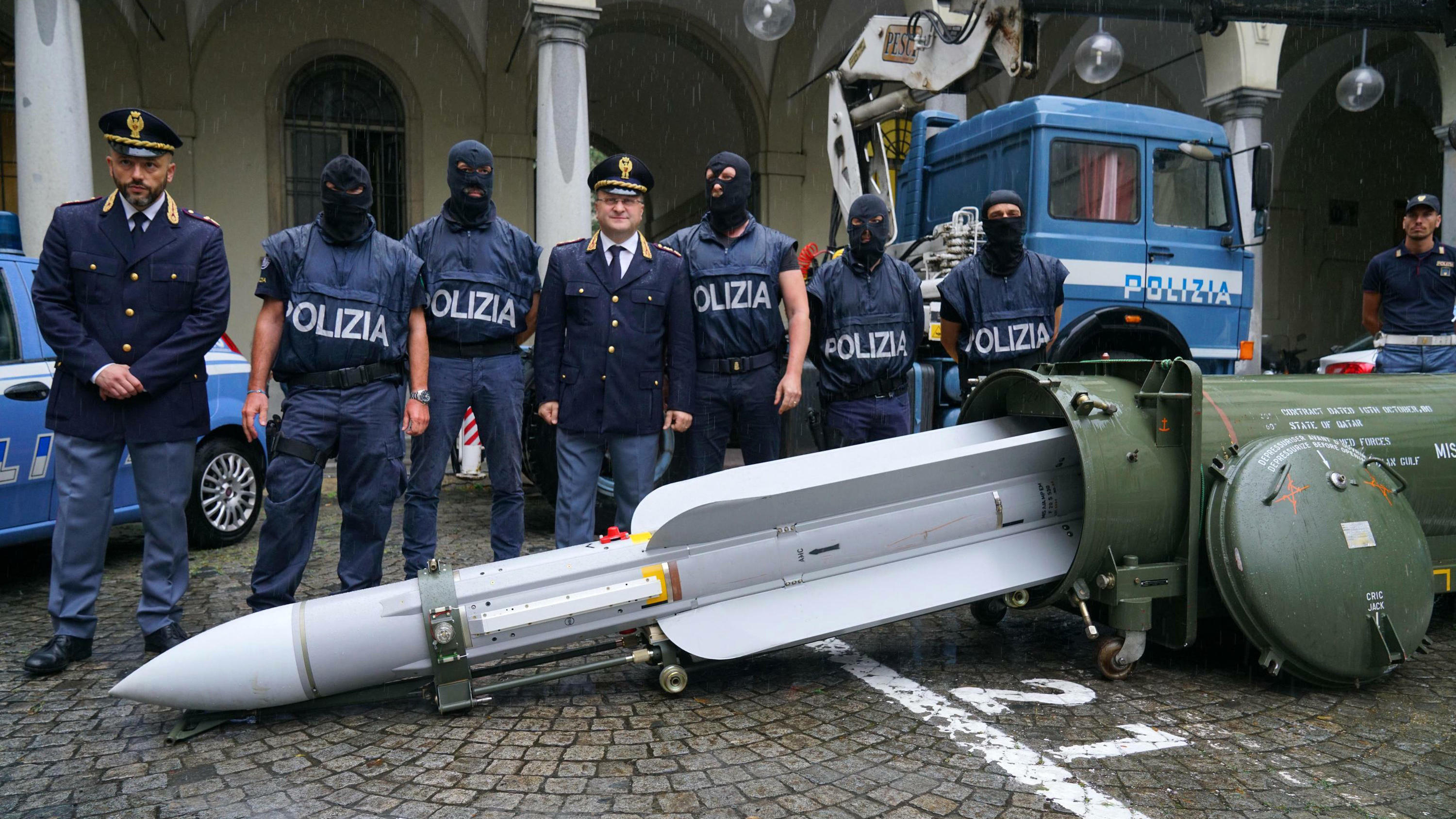 Italienische Polizei beschlagnahmt Waffensammlung von Neonazis 15.07.2019, Italien, Pavia: Polizisten stehen hinter einer Rakete, die in einem Flughafenhangar beschlagnahmt wurde. Die Polizei hat drei Männer in Norditalien festgenommen, nachdem sie einen riesigen Vorrat an automatischen Waffen, eine Rakete und N