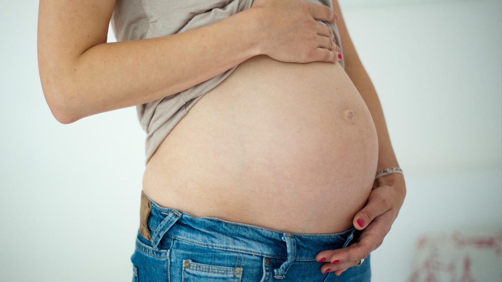 Fitnessstudio-Vertrag abschließen: Darauf müssen Sie achten! Junge Frau hält ihren Babybauch.