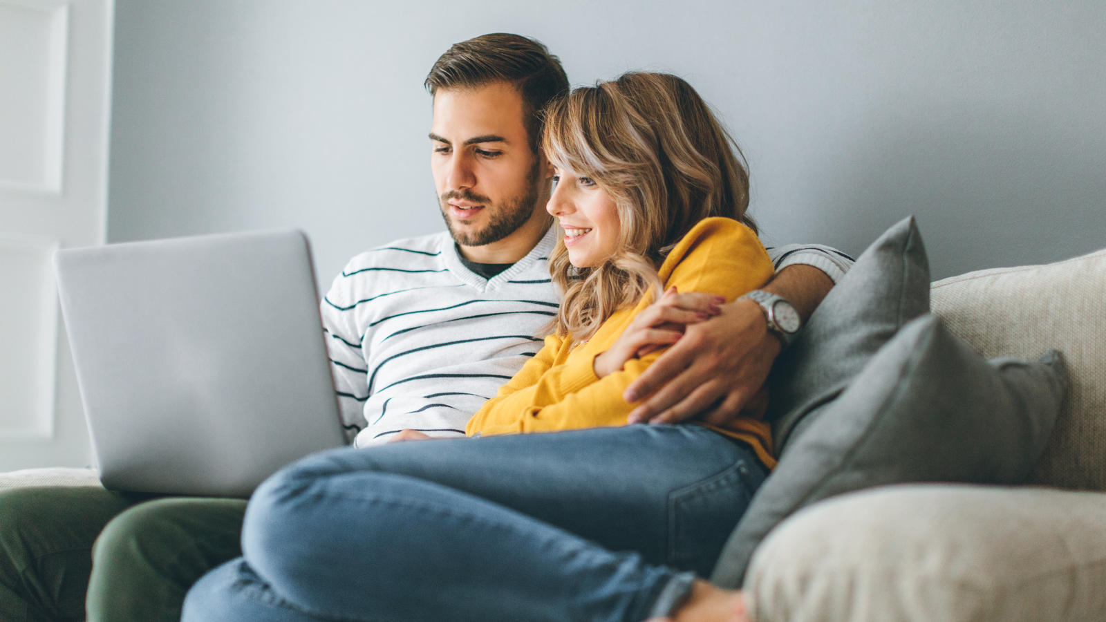 Social Media Horoskop Stier Young cheerful couple using laptop at home, paar, couch, gemütlich, online-shopping, internet, laptop