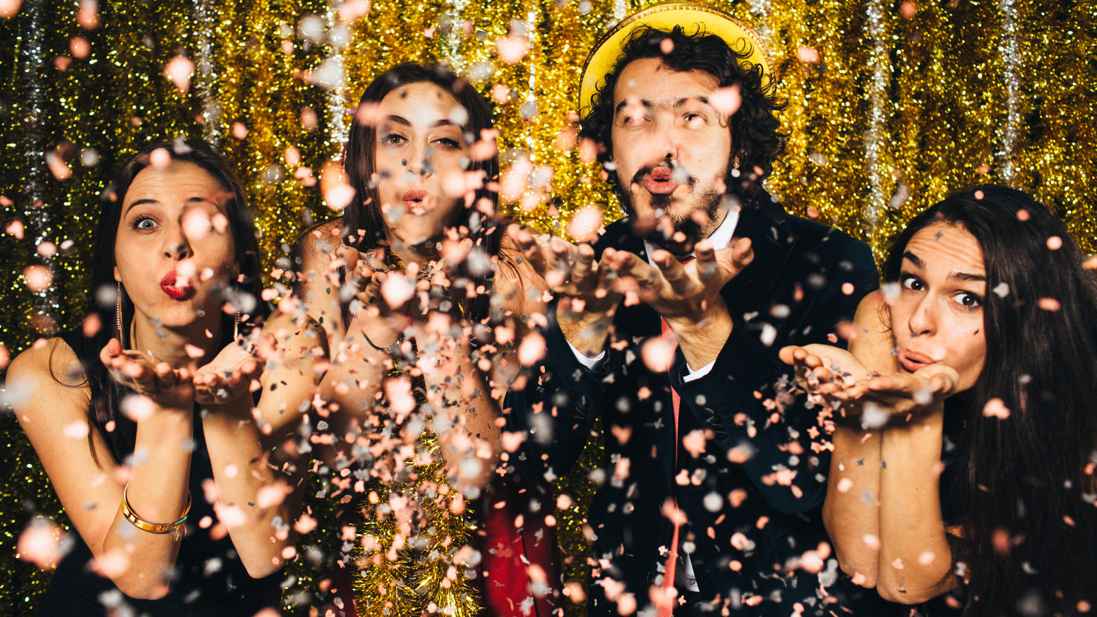 Silvesterbräuche: Das bringt uns Glück, Geld und ganz viel Liebe! Freunde pusten Konfetti zu Silvester in die Luft.