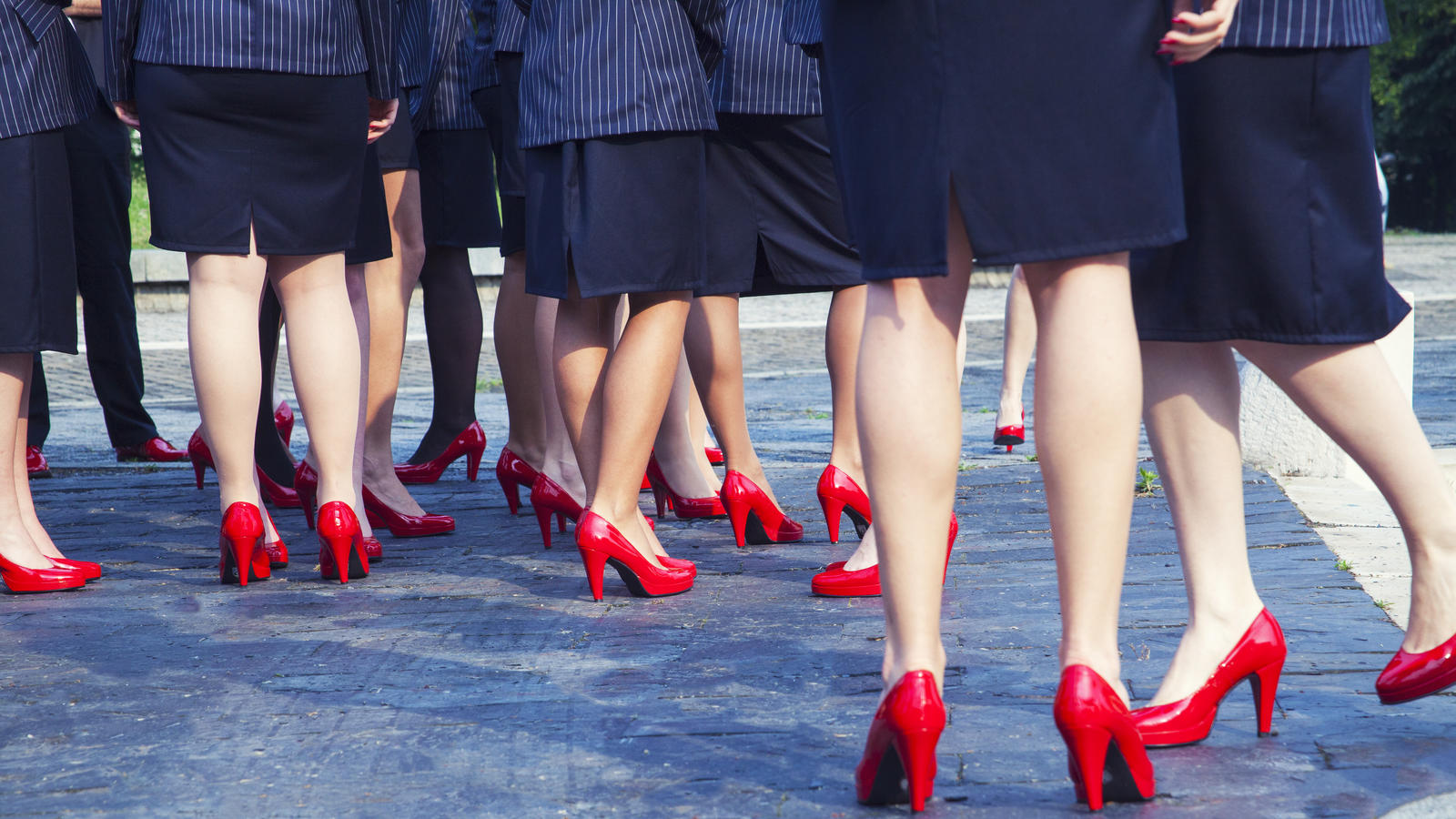 High Heels-Zwang im Job - darf der Arbeitgeber uns zwingen? Viele Frauen im Business-Look: Rote High Heels, dunkelblaues Kostüm.
