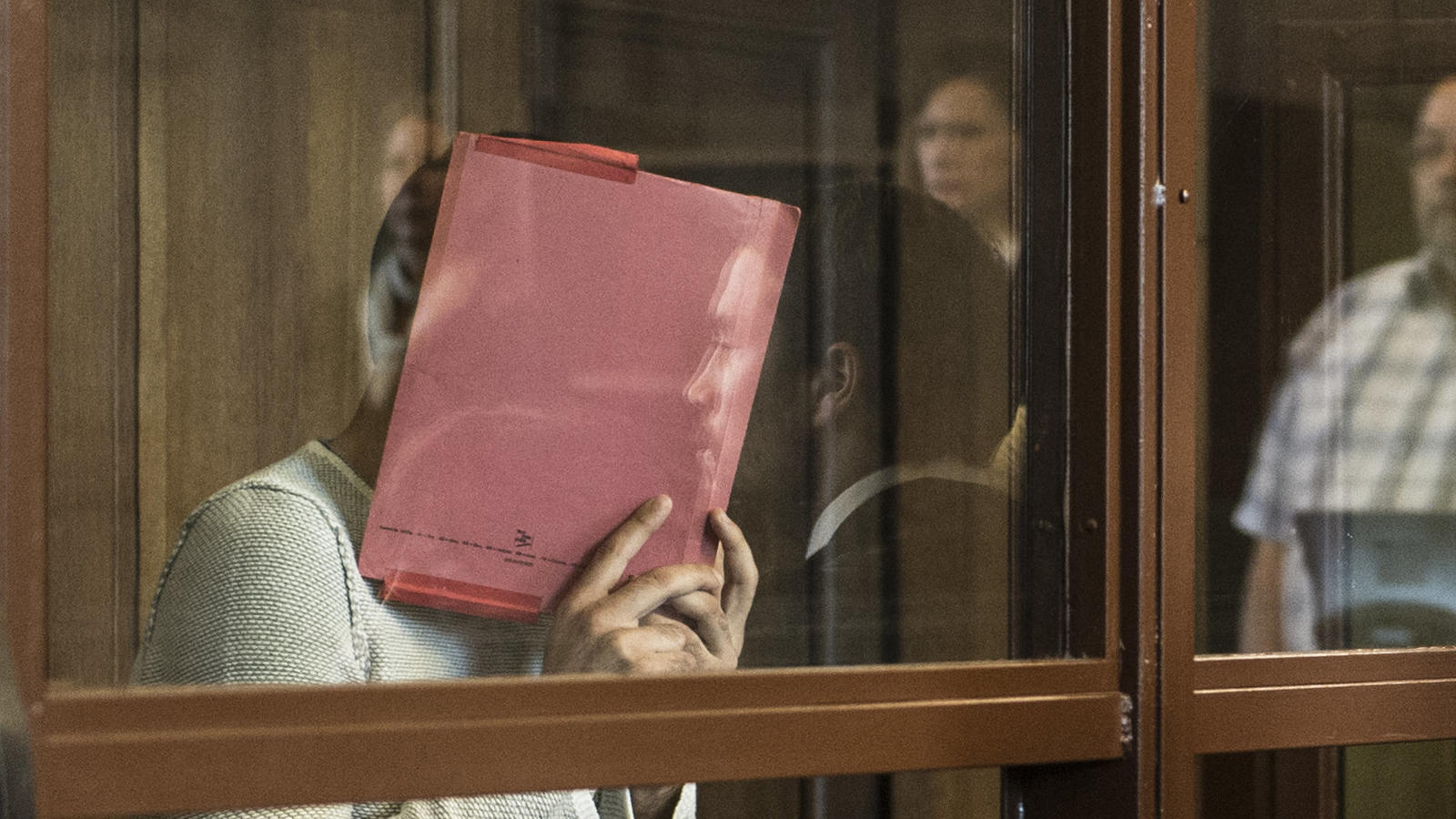 "Der normale Alltag war erst einmal weg": Opfer des Berliner U-Bahn-Treters sagt aus ARCHIV - Der Angeklagte Swetoslaw S. steht am 26.06.2017 in Berlin mit einer Mappe vor dem Gesicht hinter einer Glasscheibe in einem Gerichtssaal und muss sich wegen gefährlicher Körperverletzung verantworten. Am 29. Juni soll der Prozess gegen 28-Jä