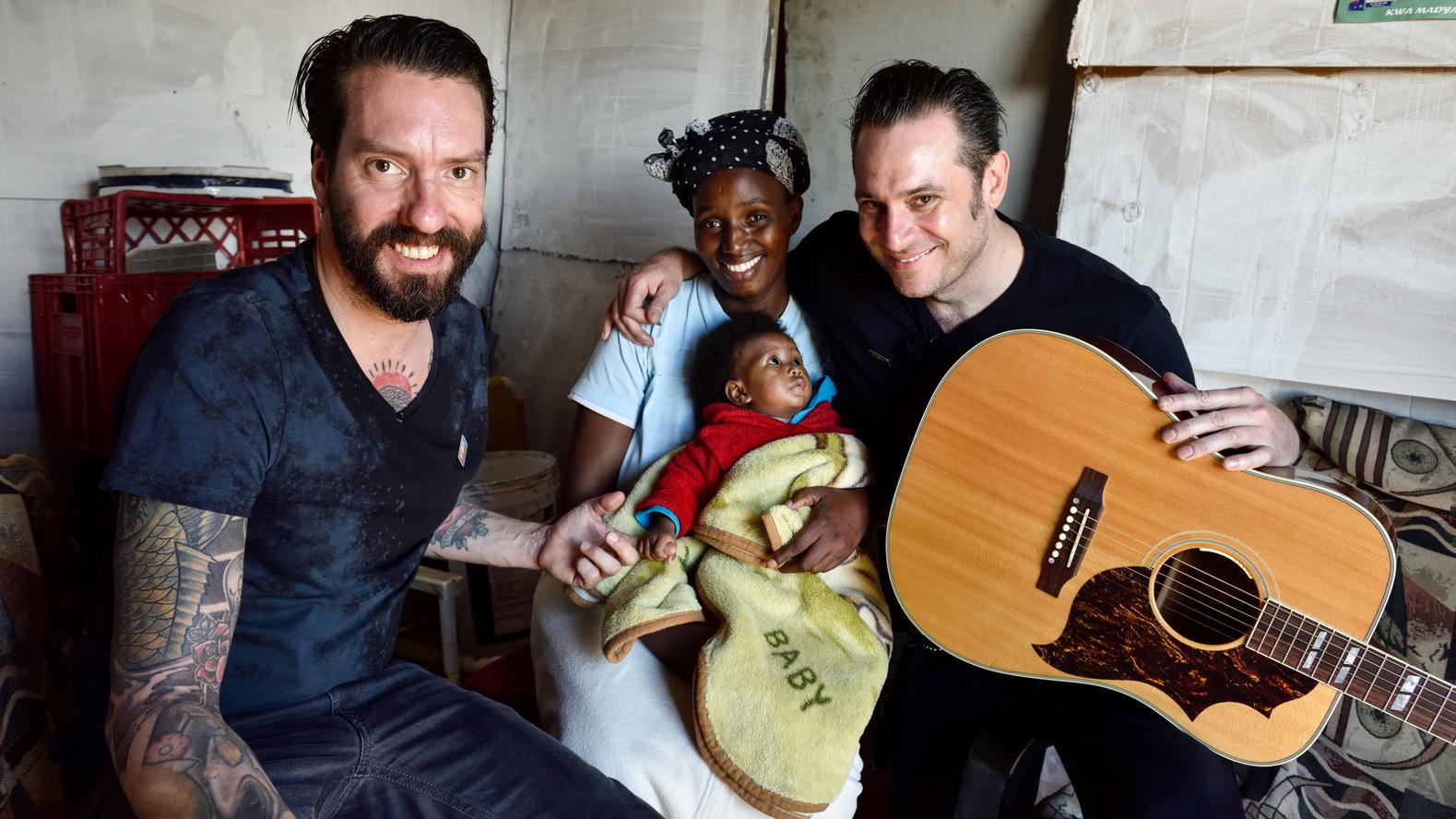 Projektpaten von „RTL – Wir helfen Kindern“: Emotionale Grenzerfahrung für „The BossHoss“ im Township! Alec Völkel (l) und Sascha Vollmer - The BossHoss - sind Paten der Stiftung "RTL - Wir helfen Kindern". Sie besuchen Tholiswa Mtando (32) mit ihrer Tochter Inganathi (8 Monate) im Township Masakhane in Südafrika.