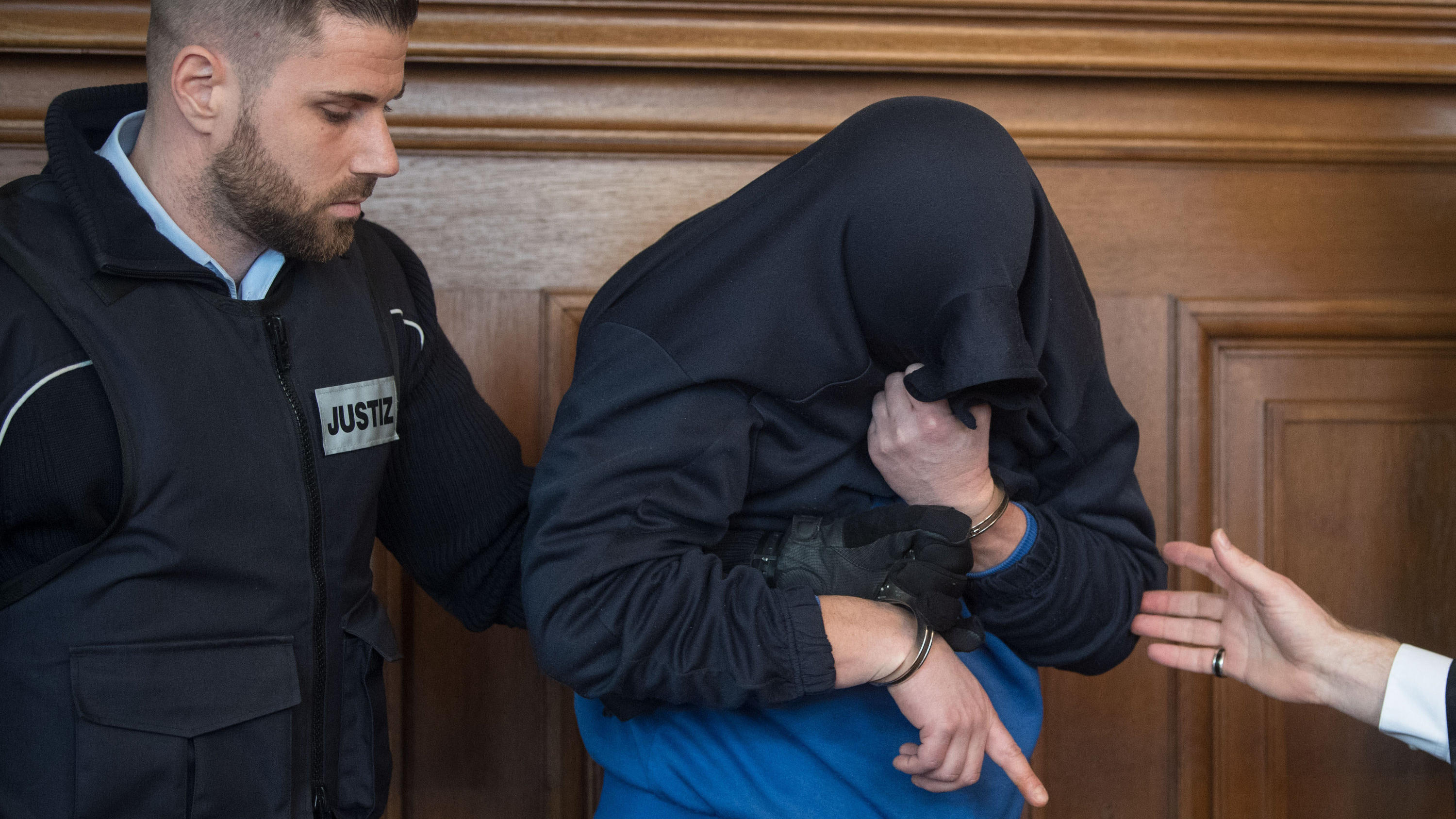 Dreifach-Mord am Tag der Einschulung: Prozessbeginn gegen Vater (41) 16.03.2018, Baden-Württemberg, Rottweil: Der Angeklagte im Prozess um einen Dreifach-Mord (M) wird im Landgericht im Gerichtssaal von Justizbeamten an seinen Platz geführt. Ein halbes Jahr nach dem Familiendrama von Villingendorf mit drei Toten hat d