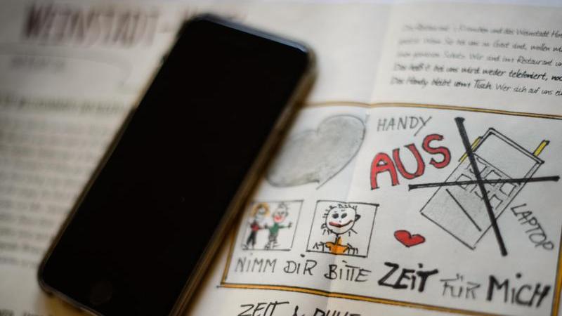 "Handy aus": Hotel verbietet Handys und Laptops Ein Handy liegt auf einer Broschüre