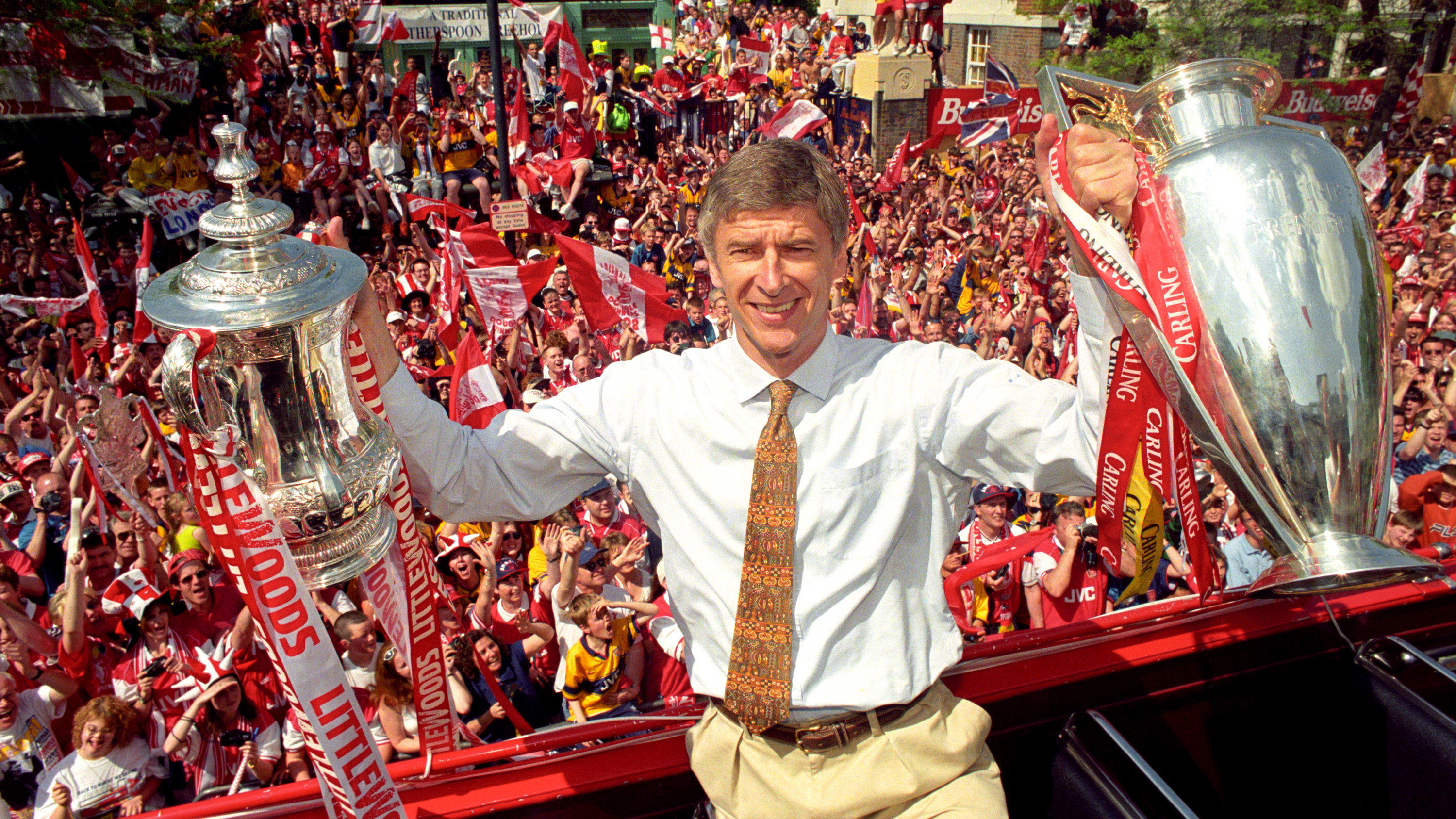 Nach 22 Jahren: Arsene Wenger tritt als Trainer bei Arsenal zurück ARCHIV - 17.05.1998, Großbritannien, London: Arsène Wenger, Trainer des FC Arsenal, hält die Pokale vom FA Cup und vom League Cup, während im Hintergrund die Fans jubeln. Arsène Wenger hört nach fast 22 Jahren als Trainer des FC Arsenal am Ende diese