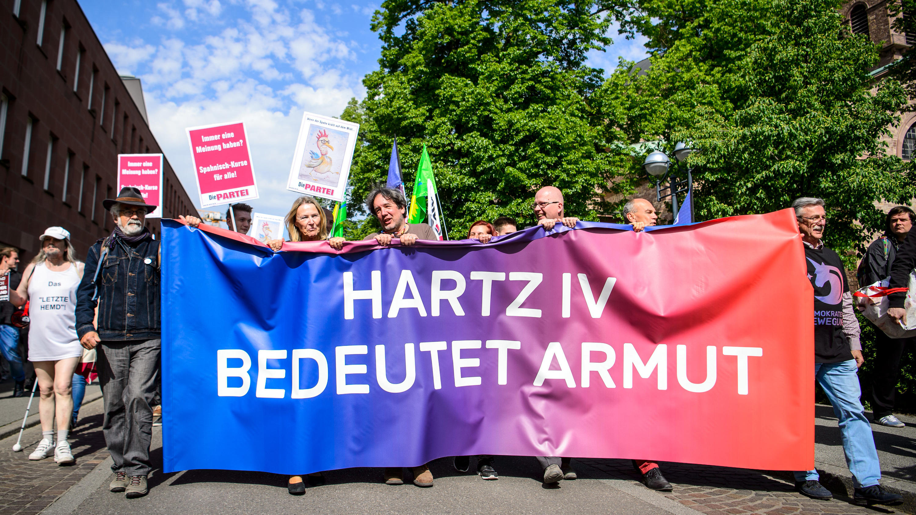 SPD-Chefin Nahles will "Bürgergeld" statt Hartz IV 28.04.2018, Baden-Württemberg, Karlsruhe: Demonstranten tragen ein Banner mit der Aufschrift "Hartz IV bedeutet Armut" vor dem Treffen von Bundesgesundheitsminister Spahn mit der Hartz-IV-Kritikerin Schlensog. Vor dem Treffen haben etwa 100 Menschen