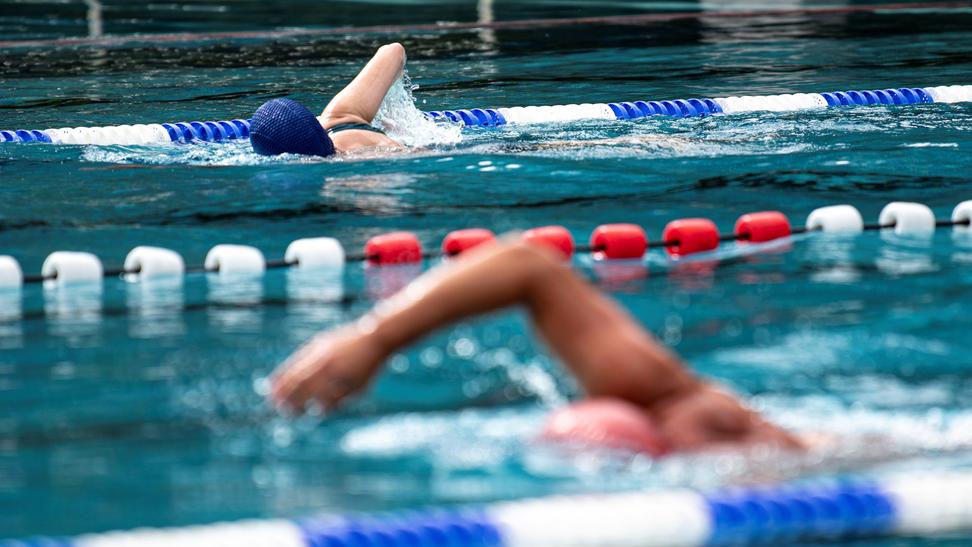 Zwei Schwimmer ziehen im Freibad ihre Bahnen