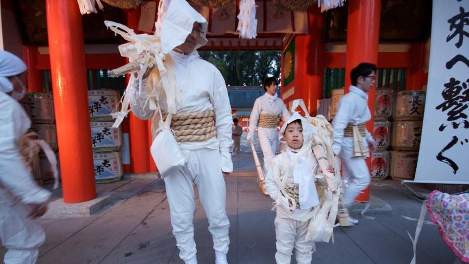 Angezogen in weißen Gewändern, die für Reinheit stehen und mit Strohseilen um ihre Hüften für heiligen Hchutz tragen Vater und Sohn Fackeln zum Feuerritual in Oto Matsuri in Japan