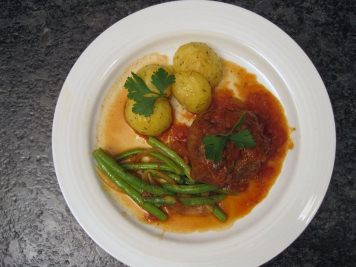 Lammbraten mit Tomaten und Zwiebeln, dazu Kartoffeln und Bohnen