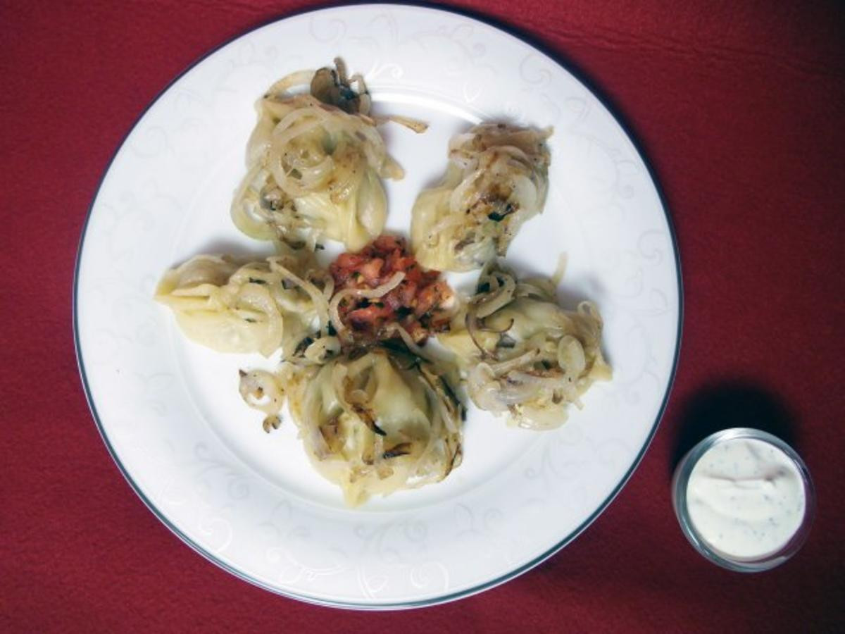Manti mit gebratenen Zwiebelringen und verschiedenen Soßen