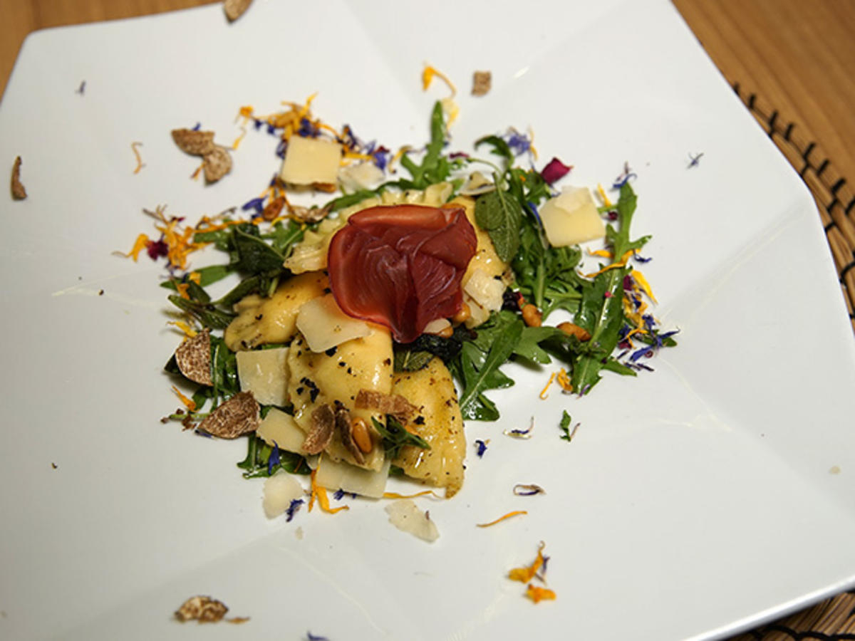 Bild zu: "Lavastein-verfeinerte Trüffelravioli in Salbeijus mit Parmesan und Bresaola-Rose"