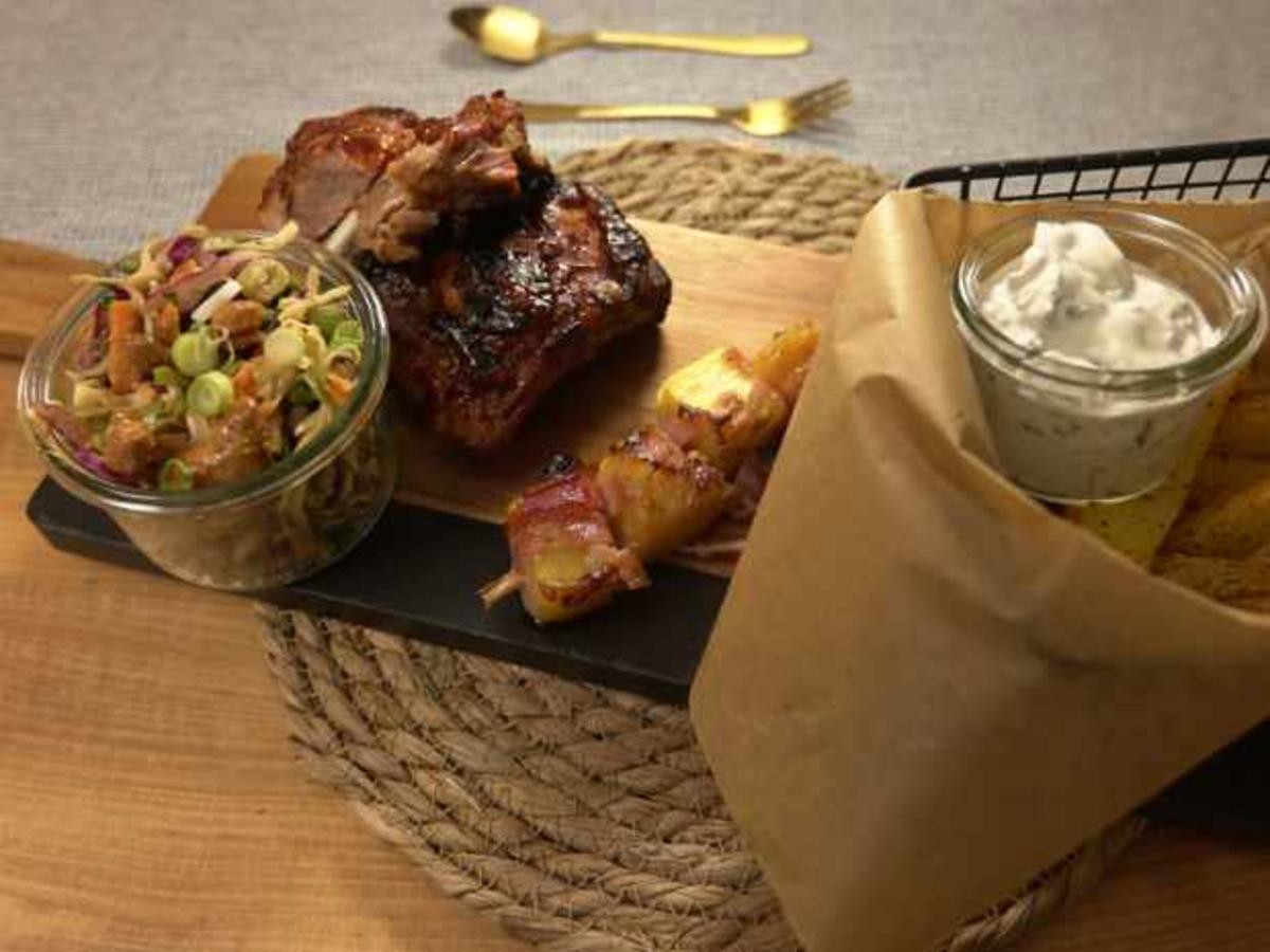 Rippchen mit Kartoffelecken, Coleslaw und Ananas in Speck