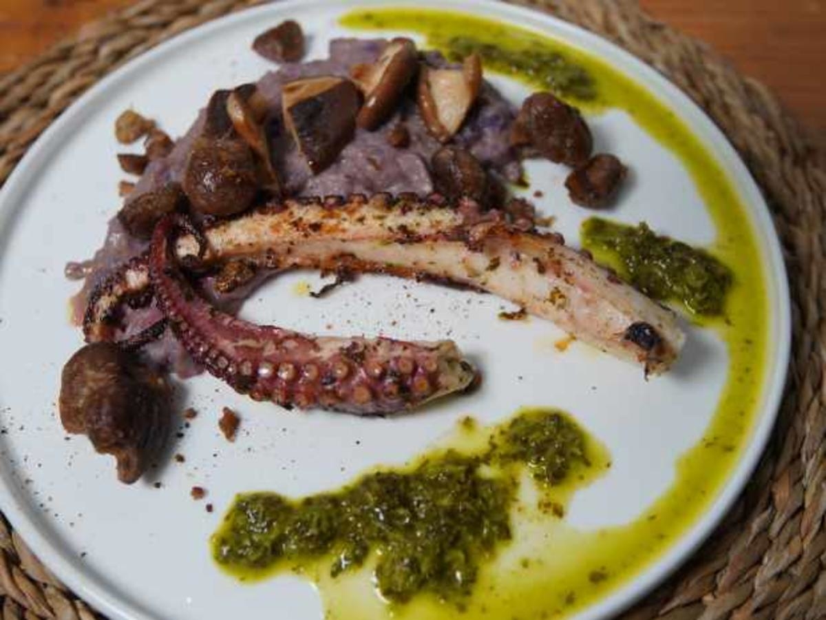 Oktopus mit Maronen und Pilzen auf lila Kartoffelpüree