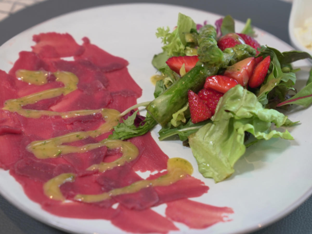 Wildcarpaccio mit Wildkräutersalat, garniert mit Erdbeeren und Spargel