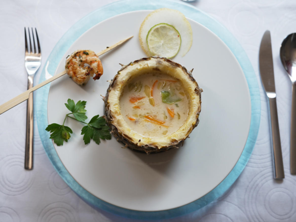 Edelfischsuppe in der Ananashälfte mit Garnelen Garnitur